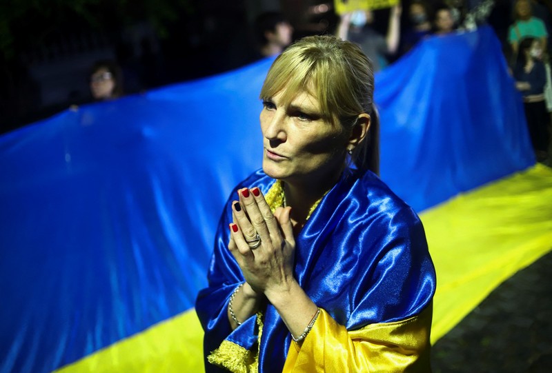 Demonstran pro-Ukraina mengibarkan bendera besar Ukraina di Times Square New York, Kamis, 24 Februari 2022. (AP/Seth Wenig)