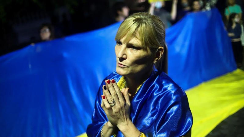 Demonstran pro-Ukraina mengibarkan bendera besar Ukraina di Times Square New York, Kamis, 24 Februari 2022. (AP/Seth Wenig)