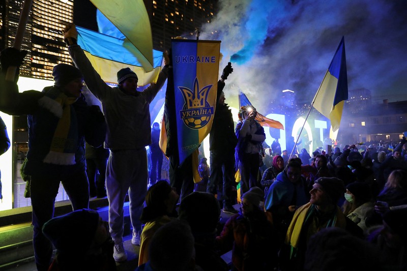 Demonstran pro-Ukraina mengibarkan bendera besar Ukraina di Times Square New York, Kamis, 24 Februari 2022. (AP/Seth Wenig)