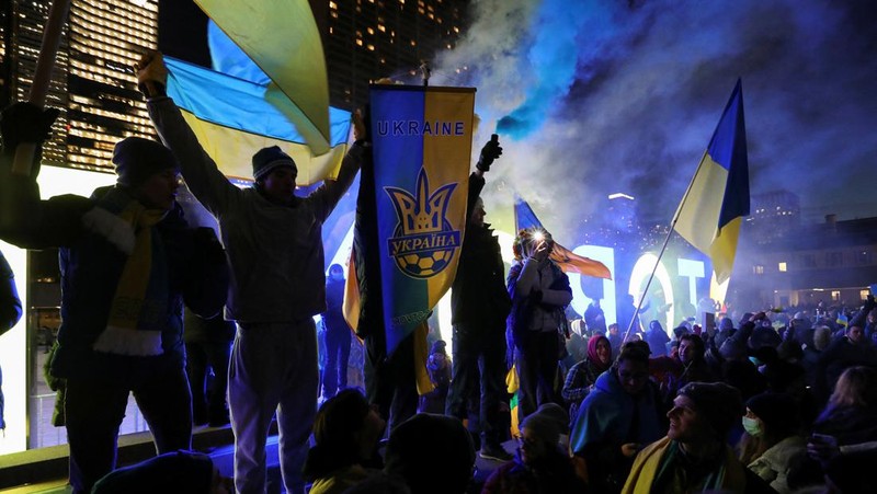 Demonstran pro-Ukraina mengibarkan bendera besar Ukraina di Times Square New York, Kamis, 24 Februari 2022. (AP/Seth Wenig)