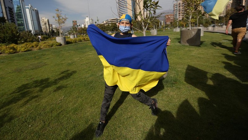 Demonstran pro-Ukraina mengibarkan bendera besar Ukraina di Times Square New York, Kamis, 24 Februari 2022. (AP/Seth Wenig)