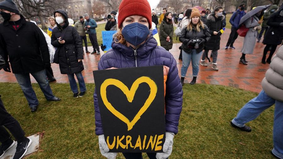 Demonstran pro-Ukraina mengibarkan bendera besar Ukraina di Times Square New York, Kamis, 24 Februari 2022. (AP/Seth Wenig)