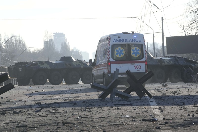 Tentara Ukraina mengambil posisi di luar fasilitas militer saat dua mobil terbakar, di sebuah jalan di Kyiv, Ukraina, Sabtu (26/2/2022). Pasukan Rusia menyerbu ke arah ibu kota Ukraina dan pertempuran jalanan pecah saat pejabat kota mendesak penduduk untuk berlindung. (AP/Emilio Morenatti)