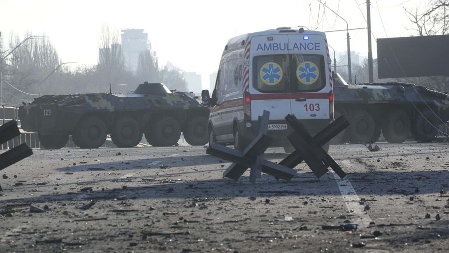 Tentara Ukraina mengambil posisi di luar fasilitas militer saat dua mobil terbakar, di sebuah jalan di Kyiv, Ukraina, Sabtu (26/2/2022). Pasukan Rusia menyerbu ke arah ibu kota Ukraina dan pertempuran jalanan pecah saat pejabat kota mendesak penduduk untuk berlindung. (AP/Emilio Morenatti)