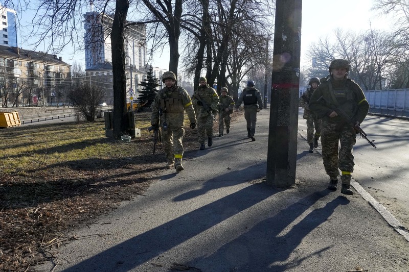 Tentara Ukraina mengambil posisi di luar fasilitas militer saat dua mobil terbakar, di sebuah jalan di Kyiv, Ukraina, Sabtu (26/2/2022). Pasukan Rusia menyerbu ke arah ibu kota Ukraina dan pertempuran jalanan pecah saat pejabat kota mendesak penduduk untuk berlindung. (AP/Emilio Morenatti)
