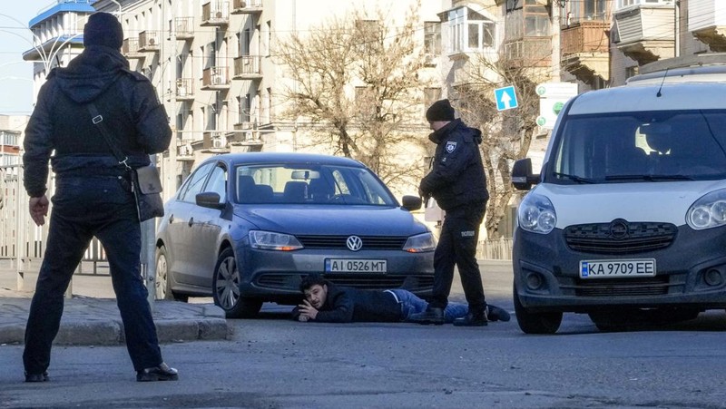 Tentara Ukraina mengambil posisi di luar fasilitas militer saat dua mobil terbakar, di sebuah jalan di Kyiv, Ukraina, Sabtu (26/2/2022). Pasukan Rusia menyerbu ke arah ibu kota Ukraina dan pertempuran jalanan pecah saat pejabat kota mendesak penduduk untuk berlindung. (AP/Emilio Morenatti)