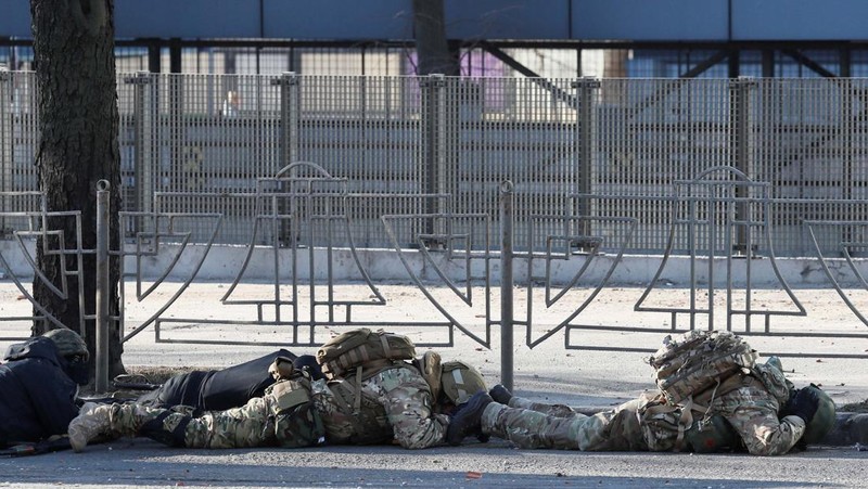 Tentara Ukraina mengambil posisi di luar fasilitas militer saat dua mobil terbakar, di sebuah jalan di Kyiv, Ukraina, Sabtu (26/2/2022). Pasukan Rusia menyerbu ke arah ibu kota Ukraina dan pertempuran jalanan pecah saat pejabat kota mendesak penduduk untuk berlindung. (AP/Emilio Morenatti)