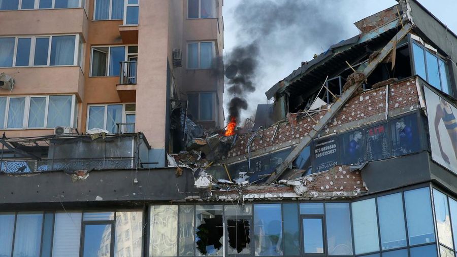 Tentara Ukraina mengambil posisi di luar fasilitas militer saat dua mobil terbakar, di sebuah jalan di Kyiv, Ukraina, Sabtu (26/2/2022). Pasukan Rusia menyerbu ke arah ibu kota Ukraina dan pertempuran jalanan pecah saat pejabat kota mendesak penduduk untuk berlindung. (AP/Emilio Morenatti)