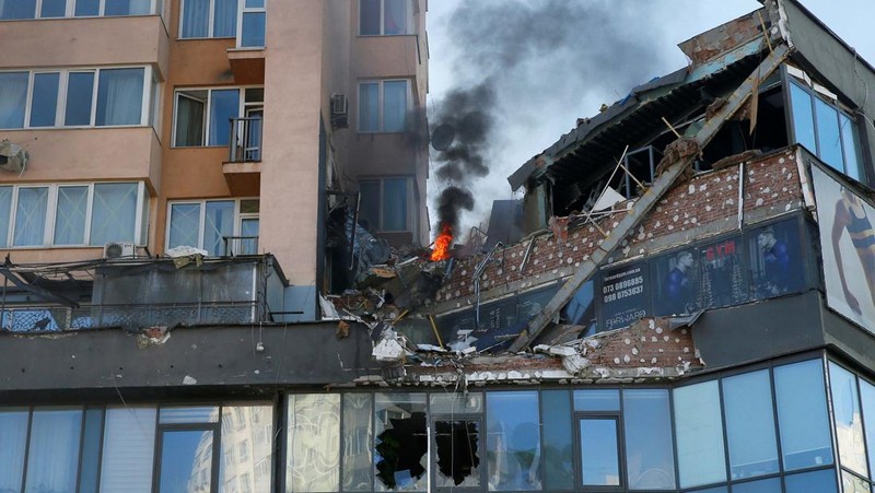 Tentara Ukraina mengambil posisi di luar fasilitas militer saat dua mobil terbakar, di sebuah jalan di Kyiv, Ukraina, Sabtu (26/2/2022). Pasukan Rusia menyerbu ke arah ibu kota Ukraina dan pertempuran jalanan pecah saat pejabat kota mendesak penduduk untuk berlindung. (AP/Emilio Morenatti)