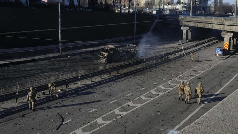 Tentara Ukraina mengambil posisi di luar fasilitas militer saat dua mobil terbakar, di sebuah jalan di Kyiv, Ukraina, Sabtu (26/2/2022). Pasukan Rusia menyerbu ke arah ibu kota Ukraina dan pertempuran jalanan pecah saat pejabat kota mendesak penduduk untuk berlindung. (AP/Emilio Morenatti)