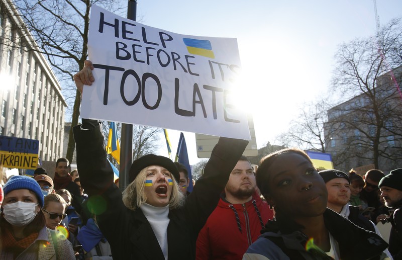 Para wanita membantu mengangkat bendera nasional Ukraina saat mereka memprotes invasi Rusia ke Ukraina, di Buenos Aires, Argentina. Jumat (25/2/2022).  (AP Photo'/Natacha Pisarenko)