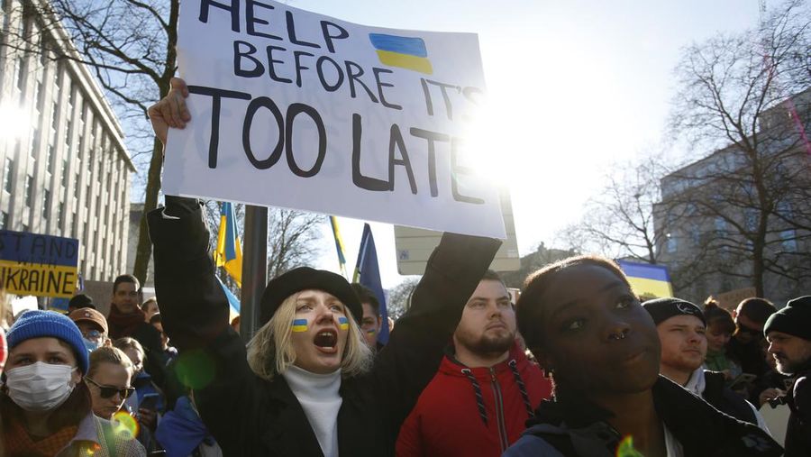 Para wanita membantu mengangkat bendera nasional Ukraina saat mereka memprotes invasi Rusia ke Ukraina, di Buenos Aires, Argentina. Jumat (25/2/2022).  (AP Photo'/Natacha Pisarenko)