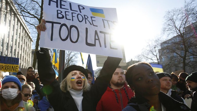 Para wanita membantu mengangkat bendera nasional Ukraina saat mereka memprotes invasi Rusia ke Ukraina, di Buenos Aires, Argentina. Jumat (25/2/2022).  (AP Photo'/Natacha Pisarenko)