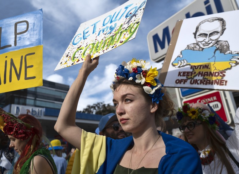 Demo Tolak Invasi Rusia Terhadap Ukraina di Buenos Aires, Argentina Para wanita membantu mengangkat bendera nasional Ukraina saat mereka memprotes invasi Rusia ke Ukraina, di Buenos Aires, Argentina. Jumat (25/2/2022). (AP Photo'/Natacha Pisarenko)