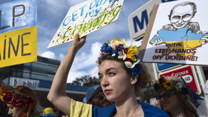 Para wanita membantu mengangkat bendera nasional Ukraina saat mereka memprotes invasi Rusia ke Ukraina, di Buenos Aires, Argentina. Jumat (25/2/2022).  (AP Photo'/Natacha Pisarenko)