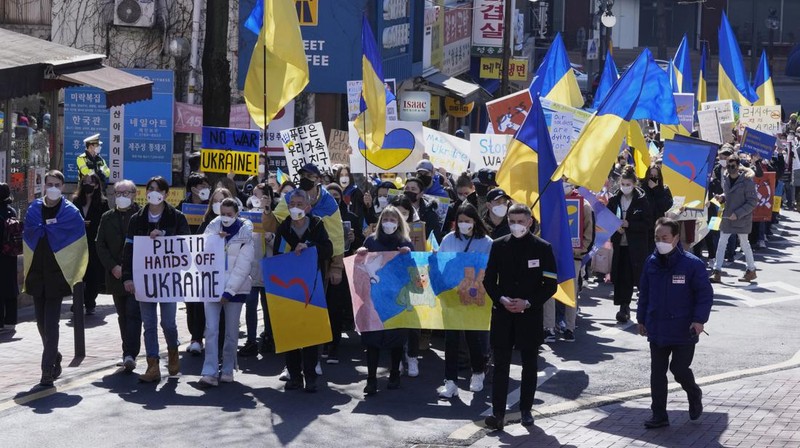 Para wanita membantu mengangkat bendera nasional Ukraina saat mereka memprotes invasi Rusia ke Ukraina, di Buenos Aires, Argentina. Jumat (25/2/2022).  (AP Photo'/Natacha Pisarenko)