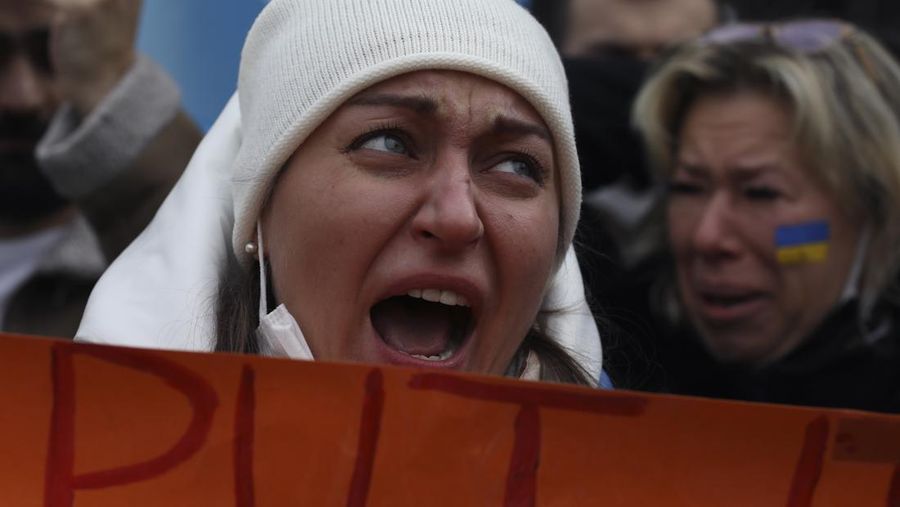 Para wanita membantu mengangkat bendera nasional Ukraina saat mereka memprotes invasi Rusia ke Ukraina, di Buenos Aires, Argentina. Jumat (25/2/2022).  (AP Photo'/Natacha Pisarenko)
