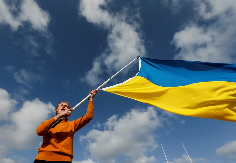 Demo Tolak Invasi Rusia Terhadap Ukraina di Buenos Aires, Argentina Para wanita membantu mengangkat bendera nasional Ukraina saat mereka memprotes invasi Rusia ke Ukraina, di Buenos Aires, Argentina. Jumat (25/2/2022). (AP Photo'/Natacha Pisarenko)