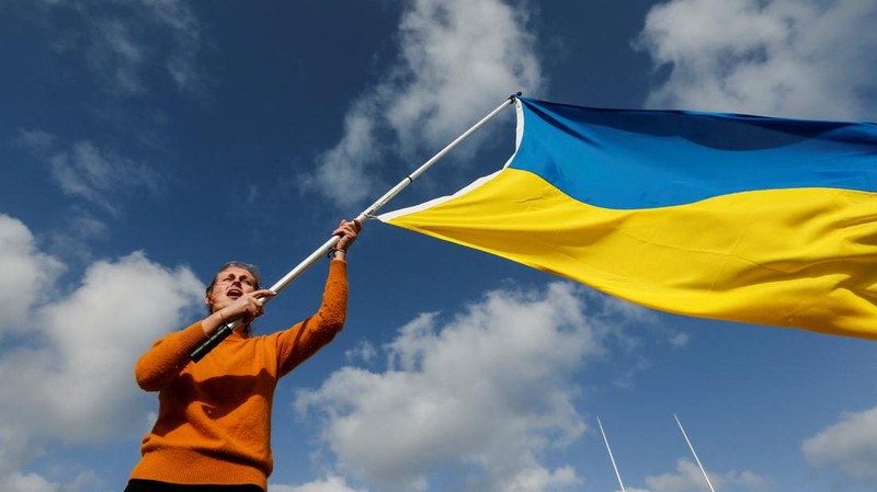 Para wanita membantu mengangkat bendera nasional Ukraina saat mereka memprotes invasi Rusia ke Ukraina, di Buenos Aires, Argentina. Jumat (25/2/2022).  (AP Photo'/Natacha Pisarenko)