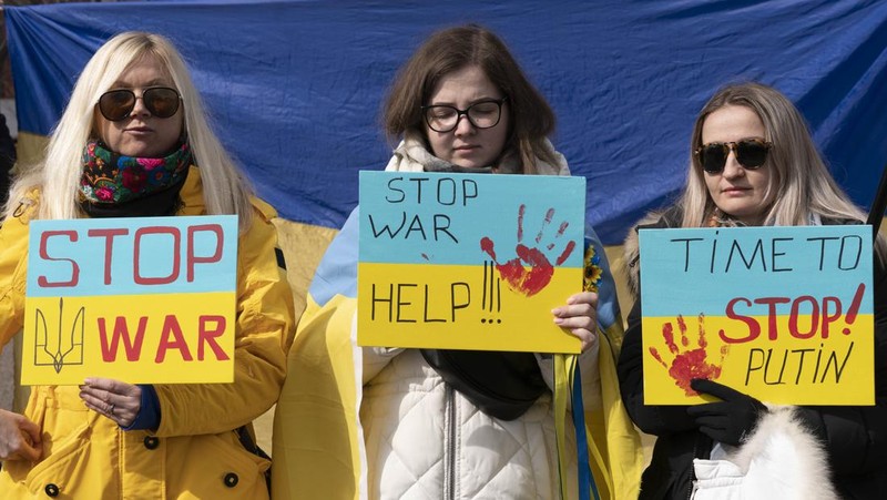 Para wanita membantu mengangkat bendera nasional Ukraina saat mereka memprotes invasi Rusia ke Ukraina, di Buenos Aires, Argentina. Jumat (25/2/2022).  (AP Photo'/Natacha Pisarenko)