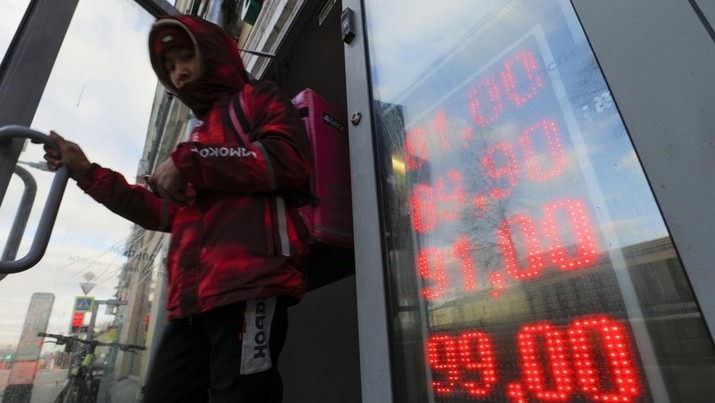 A food delivery man leaves an exchange office with screen showing the currency exchange rates of U.S. Dollar and Euro to Russian Rubles in Moscow, Russia, Thursday, Feb. 24, 2022. The Russian ruble nosedived at the news of the Russian attack on Ukraine, although it has recovered some of the losses thanks to a massive intervention by the country's Central Bank. (AP Photo/Alexander Zemlianichenko Jr)