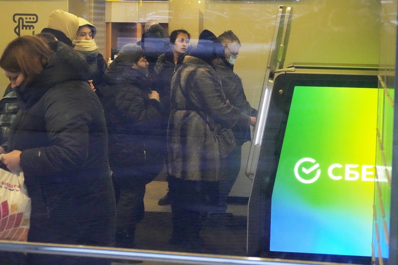 People stand in line to withdraw money from an ATM in Sberbank in St. Petersburg, Russia, Friday, Feb. 25, 2022. Russians flocked to banks and ATMs on Thursday and Friday shortly after Russia launched an attack on Ukraine and the West announced crippling sanctions. According to Russia's Central Bank, on Thursday alone Russians have withdrawn 111 billion rubles (about $1.3 billion) in cash. (AP Photo/Dmitri Lovetsky)