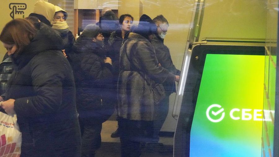 People stand in line to withdraw money from an ATM in Sberbank in St. Petersburg, Russia, Friday, Feb. 25, 2022. Russians flocked to banks and ATMs on Thursday and Friday shortly after Russia launched an attack on Ukraine and the West announced crippling sanctions. According to Russia's Central Bank, on Thursday alone Russians have withdrawn 111 billion rubles (about $1.3 billion) in cash. (AP Photo/Dmitri Lovetsky)