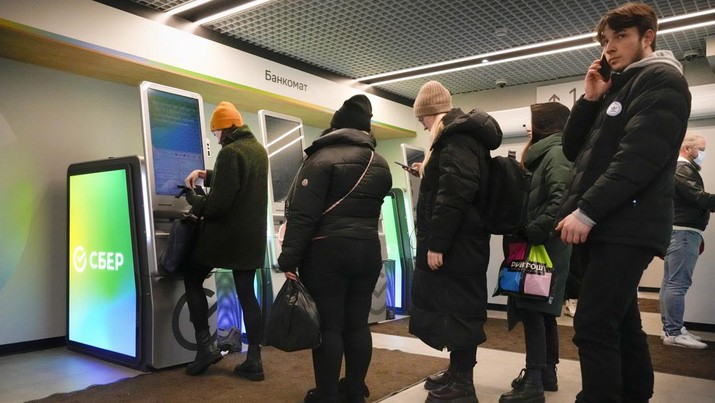 People stand in line to withdraw money from an ATM in Sberbank in St. Petersburg, Russia, Friday, Feb. 25, 2022. Russians flocked to banks and ATMs on Thursday and Friday shortly after Russia launched an attack on Ukraine and the West announced crippling sanctions. According to Russia's Central Bank, on Thursday alone Russians have withdrawn 111 billion rubles (about $1.3 billion) in cash. (AP Photo/Dmitri Lovetsky)