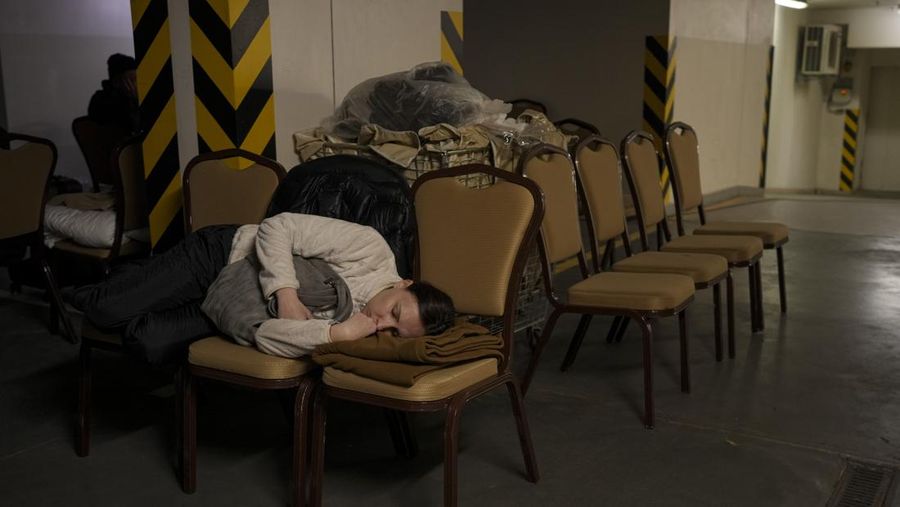 Seorang wanita tidur di kursi di tempat parkir bawah tanah hotel yang berubah menjadi tempat perlindungan bom selama serangan udara Rusia di Kyiv, Ukraina, Minggu (27/2/2022). Pria, wanita, dan anak-anak yang ketakutan mencari keselamatan di dalam dan di bawah tanah, dan pemerintah mempertahankan jam malam 39 jam untuk menjauhkan orang-orang dari jalanan karena lebih dari 150.000 orang Ukraina melarikan diri ke negara-negara tetangga dan PBB memperingatkan jumlah itu bisa bertambah menjadi 4 juta jika pertempuran meningkat. (AP Photo/Vadim Ghirda)