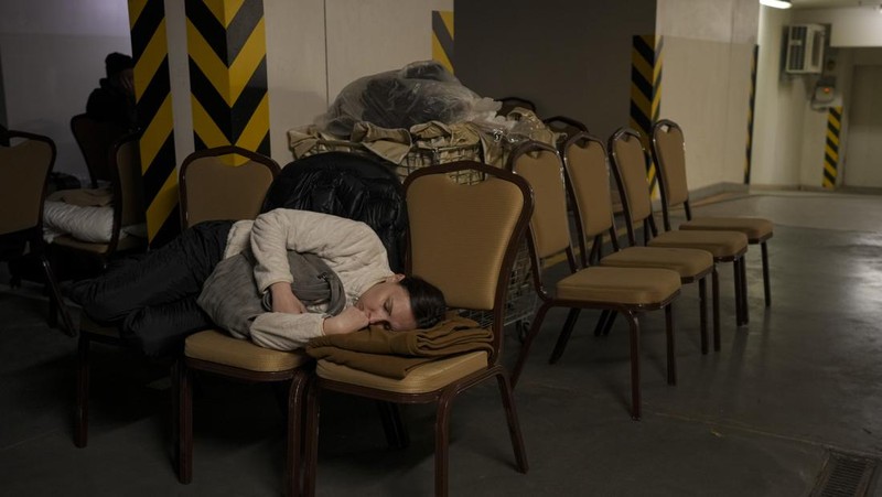 Seorang wanita tidur di kursi di tempat parkir bawah tanah hotel yang berubah menjadi tempat perlindungan bom selama serangan udara Rusia di Kyiv, Ukraina, Minggu (27/2/2022). Pria, wanita, dan anak-anak yang ketakutan mencari keselamatan di dalam dan di bawah tanah, dan pemerintah mempertahankan jam malam 39 jam untuk menjauhkan orang-orang dari jalanan karena lebih dari 150.000 orang Ukraina melarikan diri ke negara-negara tetangga dan PBB memperingatkan jumlah itu bisa bertambah menjadi 4 juta jika pertempuran meningkat. (AP Photo/Vadim Ghirda)