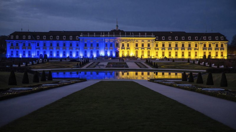 Seorang pria berlari di sepanjang trotoar di seberang Gedung Opera yang diterangi dengan warna bendera nasional Ukraina sebagai dukungan solidaritas atas invasi Rusia di Sydney, Australia, Senin (28/2/2022). (AP Photo /Mark Baker)
