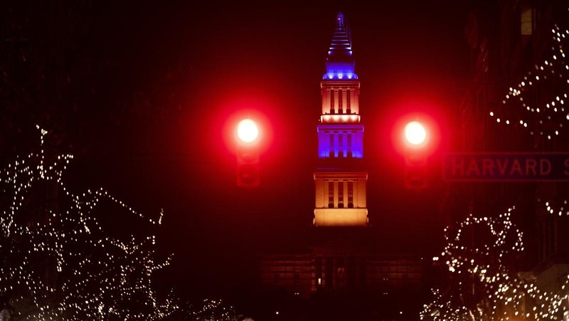 Seorang pria berlari di sepanjang trotoar di seberang Gedung Opera yang diterangi dengan warna bendera nasional Ukraina sebagai dukungan solidaritas atas invasi Rusia di Sydney, Australia, Senin (28/2/2022). (AP Photo /Mark Baker)