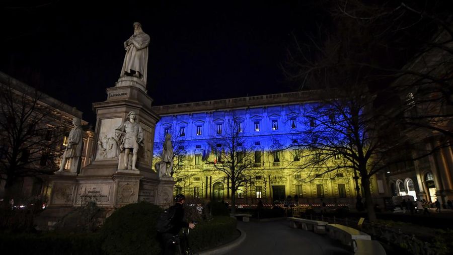 Seorang pria berlari di sepanjang trotoar di seberang Gedung Opera yang diterangi dengan warna bendera nasional Ukraina sebagai dukungan solidaritas atas invasi Rusia di Sydney, Australia, Senin (28/2/2022). (AP Photo /Mark Baker)