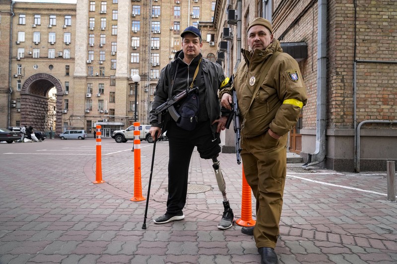Anggota pertahanan sipil bersenjata berpose untuk foto saat berpatroli di jalan yang kosong karena jam malam di Kyiv, Ukraina,  Minggu (27/2/2022).  (AP Photo/Efrem Lukatsky)