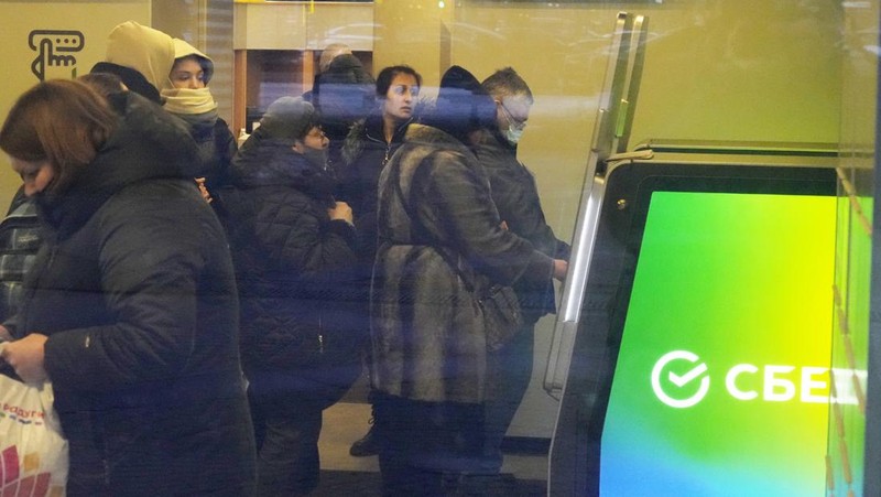 People stand in line to withdraw U.S. dollars and Euros from an ATM in St. Petersburg, Russia, Friday, Feb. 25, 2022. Ordinary Russians faced the prospect of higher prices and crimped foreign travel as Western sanctions over the invasion of Ukraine sent the ruble plummeting, leading uneasy people to line up at banks and ATMs on Monday in a country that has seen more than one currency disaster in the post-Soviet era. (AP Photo/Dmitri Lovetsky)