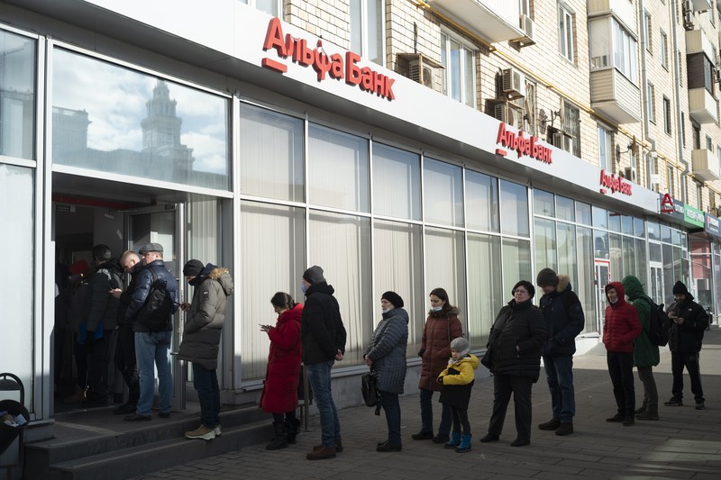 People stand in line to withdraw U.S. dollars and Euros from an ATM in St. Petersburg, Russia, Friday, Feb. 25, 2022. Ordinary Russians faced the prospect of higher prices and crimped foreign travel as Western sanctions over the invasion of Ukraine sent the ruble plummeting, leading uneasy people to line up at banks and ATMs on Monday in a country that has seen more than one currency disaster in the post-Soviet era. (AP Photo/Dmitri Lovetsky)