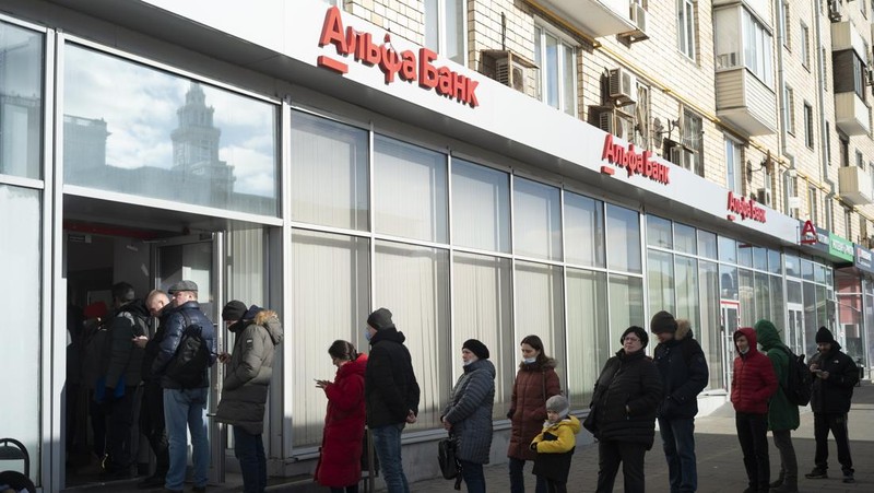 People stand in line to withdraw U.S. dollars and Euros from an ATM in St. Petersburg, Russia, Friday, Feb. 25, 2022. Ordinary Russians faced the prospect of higher prices and crimped foreign travel as Western sanctions over the invasion of Ukraine sent the ruble plummeting, leading uneasy people to line up at banks and ATMs on Monday in a country that has seen more than one currency disaster in the post-Soviet era. (AP Photo/Dmitri Lovetsky)