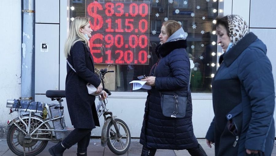 People walk past a currency exchange office screen displaying the exchange rates of U.S. Dollar and Euro to Russian Rubles in Moscow's downtown, Russia, Monday, Feb. 28, 2022. Ordinary Russians are facing the prospect of higher prices as Western sanctions over the invasion of Ukraine sent the ruble plummeting. That's led uneasy people to line up at banks and ATMs on Monday in a country that has seen more than one currency disaster in the post-Soviet era. (AP Photo/Pavel Golovkin)