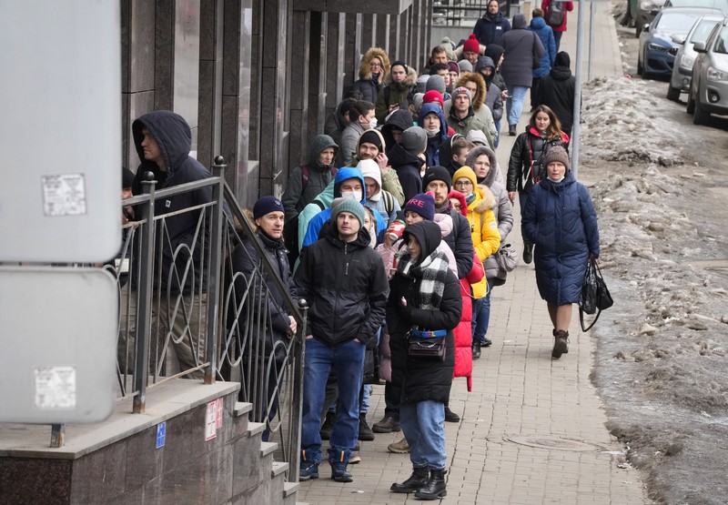 Russia Ukraine War Russia Economy People stand in line to withdraw U.S. dollars and Euros from an ATM in St. Petersburg, Russia, Friday, Feb. 25, 2022. Ordinary Russians faced the prospect of higher prices and crimped foreign travel as Western sanctions over the invasion of Ukraine sent the ruble plummeting, leading uneasy people to line up at banks and ATMs on Monday in a country that has seen more than one currency disaster in the post-Soviet era. (AP Photo/Dmitri Lovetsky)