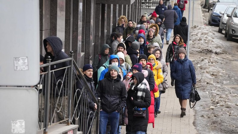 People stand in line to withdraw U.S. dollars and Euros from an ATM in St. Petersburg, Russia, Friday, Feb. 25, 2022. Ordinary Russians faced the prospect of higher prices and crimped foreign travel as Western sanctions over the invasion of Ukraine sent the ruble plummeting, leading uneasy people to line up at banks and ATMs on Monday in a country that has seen more than one currency disaster in the post-Soviet era. (AP Photo/Dmitri Lovetsky)