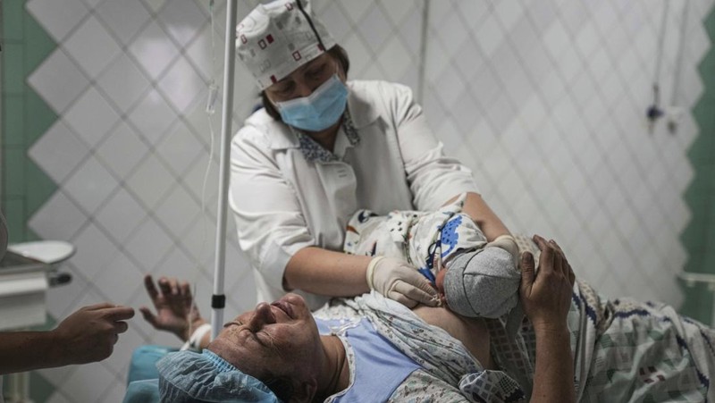 Medical workers tend to women who gave birth in a basement of a maternity hospital converted into a medical ward and used as a bomb shelter in Mariupol, Ukraine, Tuesday, March 1, 2022. Russian strikes on the key southern port city of Mariupol seriously wounded several people. (AP Photo/Evgeniy Maloletka)