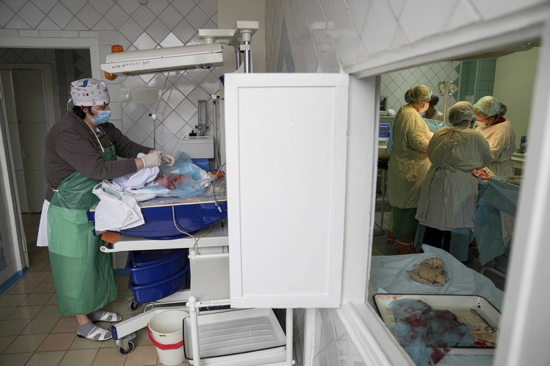 Medical workers tend to women who gave birth in a basement of a maternity hospital converted into a medical ward and used as a bomb shelter in Mariupol, Ukraine, Tuesday, March 1, 2022. Russian strikes on the key southern port city of Mariupol seriously wounded several people. (AP Photo/Evgeniy Maloletka)