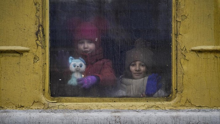 Children look out the window of an unheated Lviv bound train, in Kyiv, Ukraine, Thursday, March 3, 2022. (AP Photo/Vadim Ghirda)