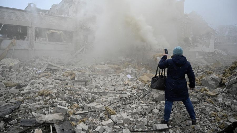 A woman uses a mobile phone while standing amidst the debris of a school building destroyed by shelling, as Russia's invasion of Ukraine continues, in Zhytomyr, Ukraine March 4, 2022. REUTERS/Viacheslav Ratynskyi