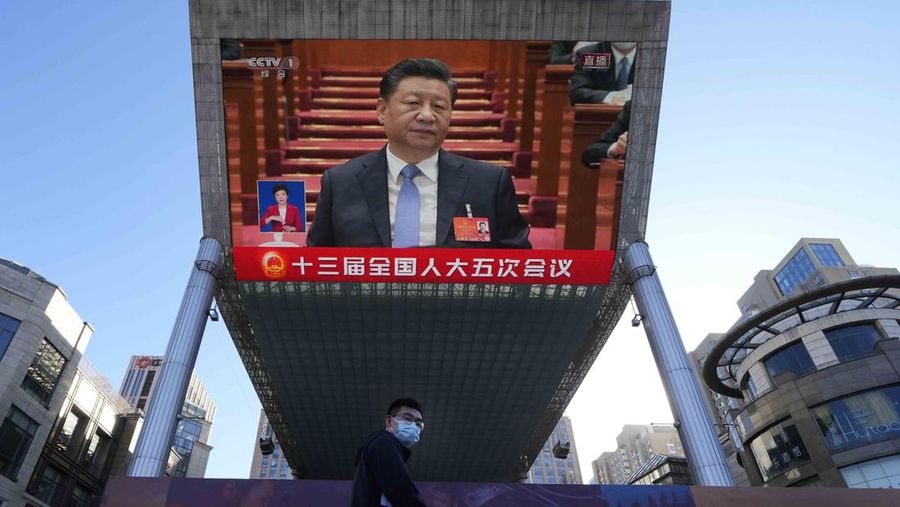 Chinese President Xi Jinping is seen on a live broadcast of the opening ceremony for the National People's Congress at a mall on Saturday, March 5, 2022, in Beijing. China on Saturday cut its annual economic growth target to its lowest level in decades as Beijing struggles to reverse a slump at a time when Russia's war on Ukraine is pushing up oil prices and roiling the global economy. (AP Photo/Ng Han Guan)