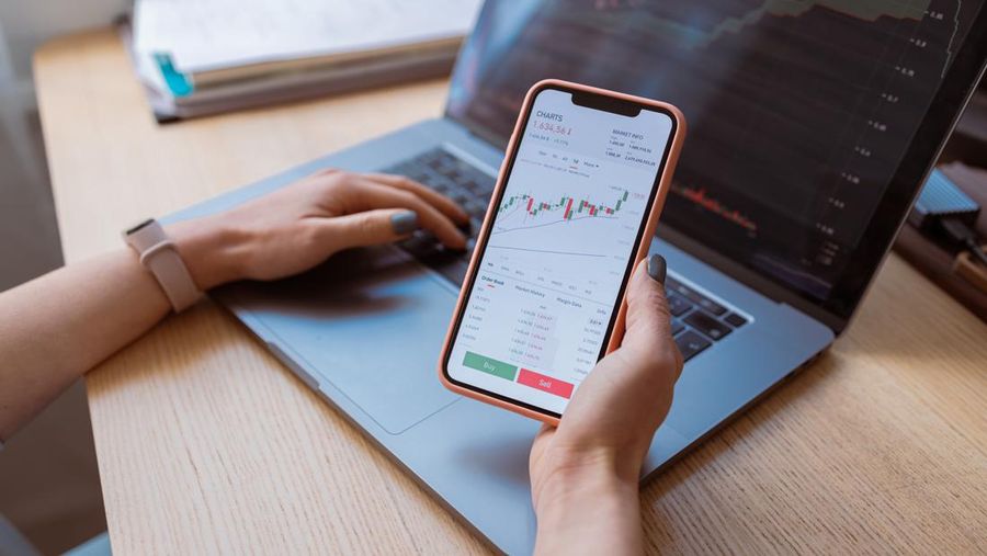 An anonymous businesswoman analyzing financial graphs on her smartphone.