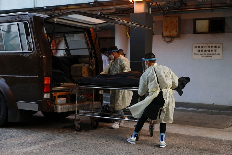 Petugas memindahkan  jenazah ke dalam kontainer berpendingin ksaat kamar jenazah kehabisan ruang di tengah wabah penyakit coronavirus (COVID-19)di Hong Kong, Sabtu (5/3/2022). (REUTERS/Tyrone Siu)