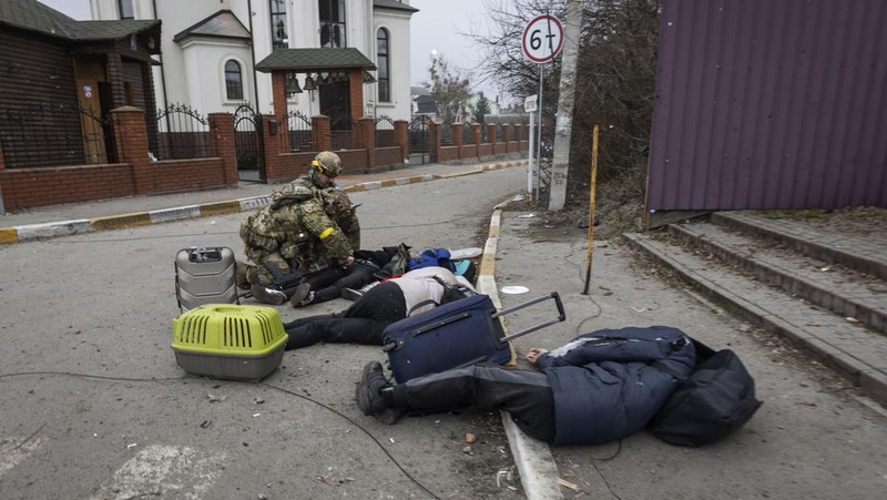 Prajurit Ukraina mencoba membantu orang-orang yang terluka akibat serangan militer Rusia di kota Irpin, Ukraina, Minggu (6/3/2022). (AP Photo/Andriy Dubchak)