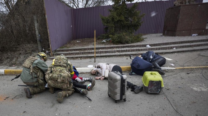 Prajurit Ukraina mencoba membantu orang-orang yang terluka akibat serangan militer Rusia di kota Irpin, Ukraina, Minggu (6/3/2022). (AP Photo/Andriy Dubchak)