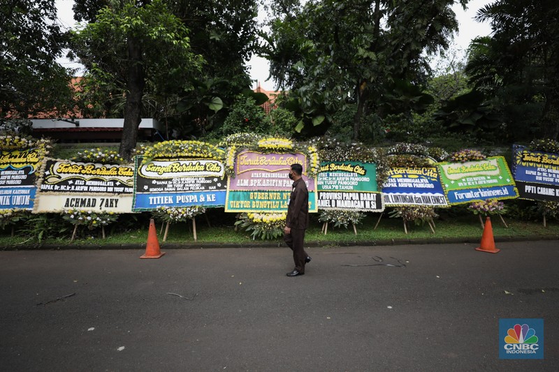 Warga melewati karangan bunga ucapan duka cita di halaman rumah duka almarhum Arifin Panigoro di Griya Jenggala, Jakarta, Senin (7/3/2022). Anggota Dewan Pertimbangan Presiden (Wantimpres) Arifin Panigoro meninggal dunia di Amerika Serikat pada Minggu (6/3/2022). Menurut penjaga keamanan setempat 